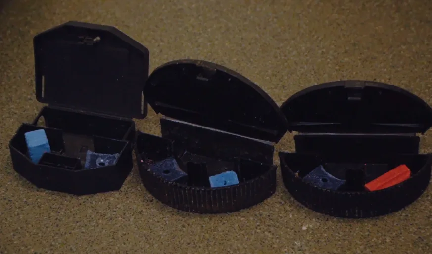 Row of black tamper-resistant bait station housings laid out before deployment