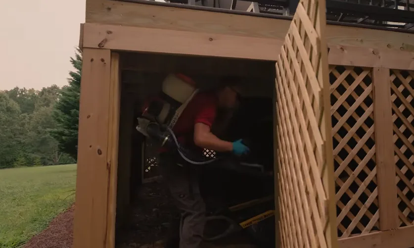 Technician entering a crawl space through a latticed access hatch