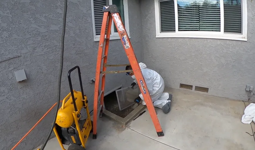 Ladder and equipment set up at an open crawl space foundation vent