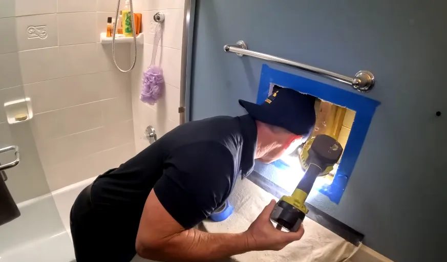 Drilling into a taped-off wall opening during a rodent damage repair