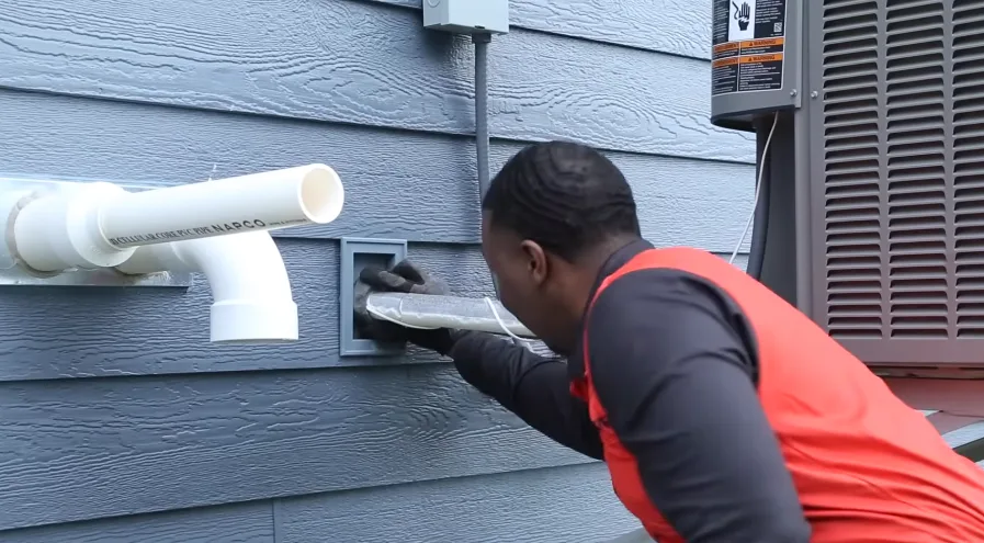 Technician working on a dryer vent where it exits exterior siding, a common rodent entry point