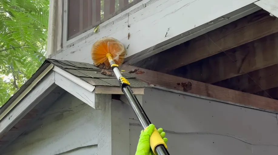 Duster on a pole reaching an eave and rafter tail along the roof line