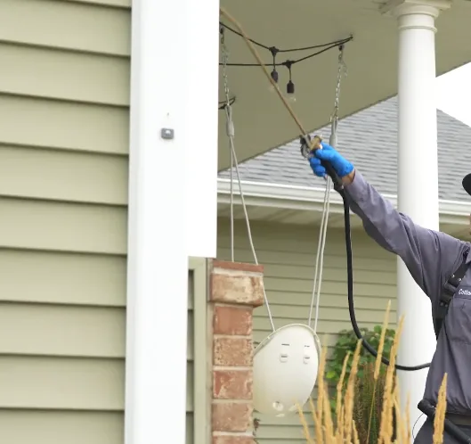 Technician treating an eave and soffit run with a long extension wand
