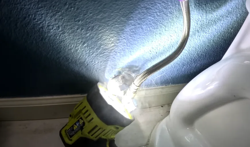 Flashlight trained on a duct penetration to check the seal around it