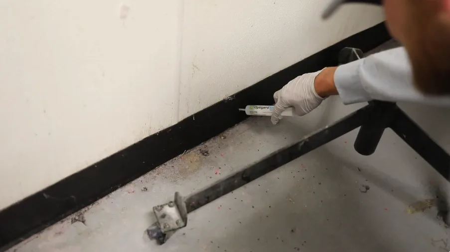 Gloved hand with a tool at the gap beside a garage door track