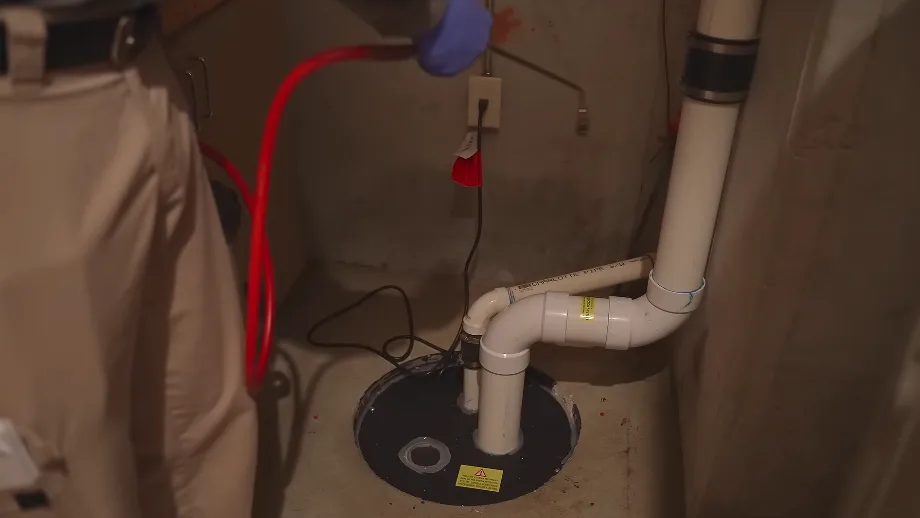 Under-sink plumbing showing the gap where pipes pass through the cabinet wall