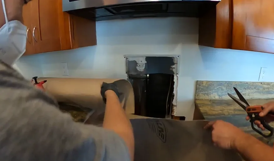Treating inside a wall cavity opened behind kitchen cabinetry